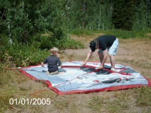 His dad showing him how to set up the tent.